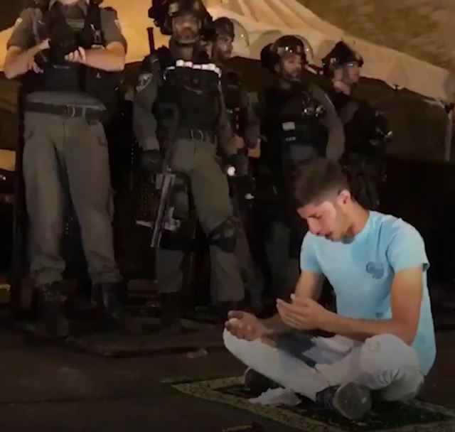 Filistinli genç, polis barikatlarının arasında seccadesine oturup bağırarak yalvardı: Allah